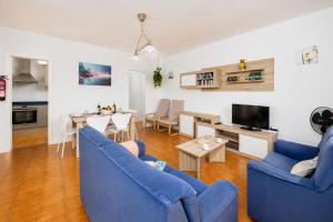 a living room with two blue chairs and a table at Villa Mares in Cala en Porter