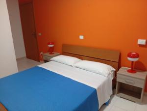 a bedroom with a blue bed and an orange wall at Costadeiapartments in Briatico