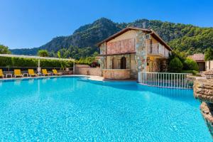 a swimming pool with a house and mountains in the background at Villa Deniz Paradise in Dalyan