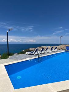 a pool with chairs and the ocean in the background at Ton Azure Hotel in Tong