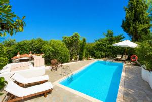 an outdoor swimming pool with chairs and an umbrella at Villa Antigoni in Alikias