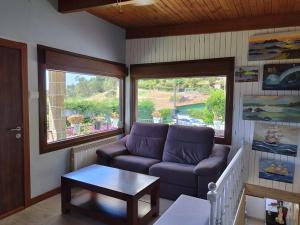 a living room with a couch and a large window at Casa a pié de playa de Cariño Doniños in Ferrol