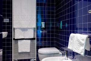 a blue tiled bathroom with a toilet and a sink at Hotel Valeria in Villa Opicina
