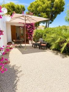 a patio with an umbrella and chairs and flowers at Les cases del vent I in L'Ametlla de Mar