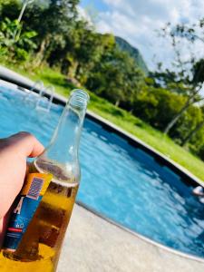 a person holding a bottle of beer next to a swimming pool at Finca Lantana Oficial in Villeta