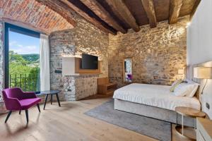a bedroom with a stone wall and a bed with a purple chair at Relais & Spa Castello di Casiglio in Erba