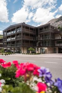 a large building with pink flowers in front of it at LA TRUGA Suite Apartments in Selva di Val Gardena