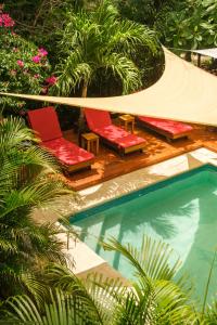 two red chairs sitting next to a swimming pool at Hotel Café Con Leche in Playa Santana