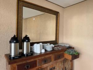 a mirror on a dresser with cups and plates on it at Pousada Ville Solare Garden in Santo Amaro