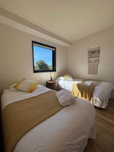 two beds in a room with a window at Cabañas Vista Volcanes del Sur in Llanquihue