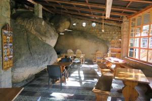 a room with wooden tables and chairs and a stone wall at Tsarasoa Lodge in Ambalavao