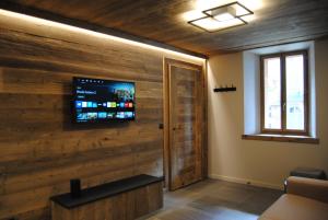 a room with a wooden wall with a flat screen tv at Mont Joly 2 in Le Baplieu