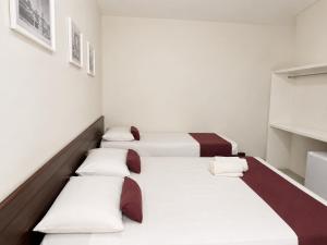 a row of beds in a room with white walls at Hotel Pousada Central in Feira de Santana +26 photos