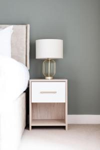 a nightstand with a lamp on it next to a bed at Super Central - Quiet - 2 Bedroom Cottage in Shrewsbury