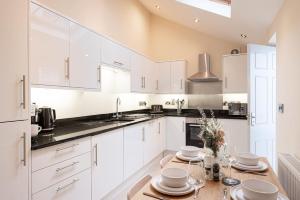 a kitchen with white cabinets and a wooden table at Super Central - Quiet - 2 Bedroom Cottage in Shrewsbury