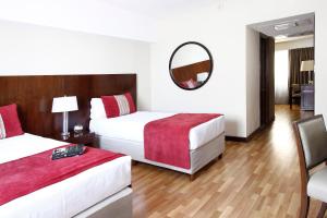 Habitación de hotel con 2 camas y espejo en Cyan Hotel de Las Americas en Buenos Aires