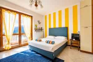 a bedroom with a bed with yellow and white stripes at Happy Guest Apartments - Lake Panorama & Pool in Riva di Solto