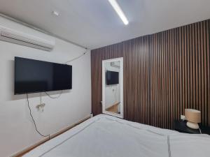 a bedroom with a flat screen tv on a wall at OSHER Simple house in Nahariyya