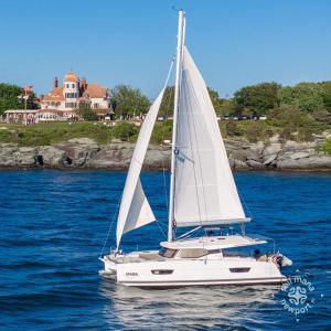 a white sailboat on the water with a house in the background at The Return - Multi-Unit Retreat - Sleeps 16 - Spa in Warren
