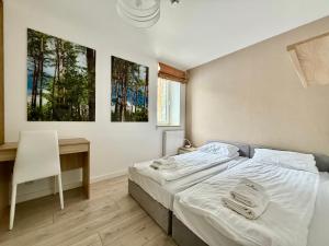 a bedroom with a bed and a desk and two paintings at Apartment & Room MARINA BORKI - Apartamenty RÓŻA WIATRÓW in Augustów +27 photos