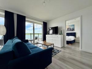 a living room with a blue couch and a bedroom at Apartment & Room MARINA BORKI - Apartamenty RÓŻA WIATRÓW in Augustów