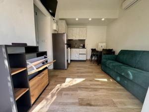 a living room with a green couch and a kitchen at Harmonia Village in Lido di Jesolo