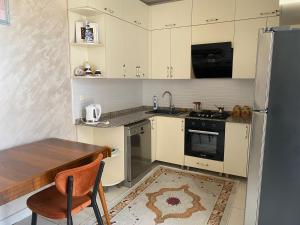 a kitchen with white cabinets and a table and a refrigerator at Hotel Tabidze in Batumi
