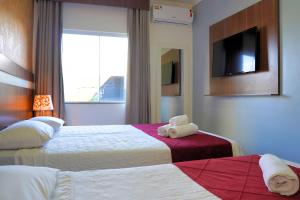 a hotel room with two beds and a television at Hotel Vivere Cataratas in Foz do Iguaçu