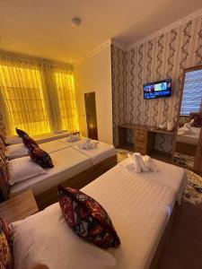 a hotel room with two beds and a television at LAYALI Boutique in Bukhara