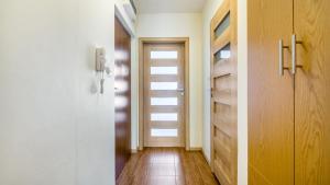 a hallway with a door and a wooden floor at Osiedle Bursztynowe in Jantar
