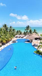 a person swimming in a swimming pool at a resort at Hotel Maragogi Beach Club in Maragogi