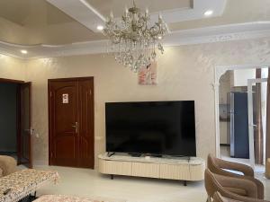 a living room with a large television and a chandelier at Hotel Tabidze in Batumi