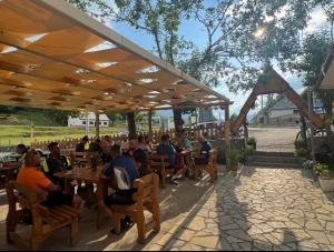 a group of people sitting at tables in a restaurant at Guesthouse Bjeshket E Arta in Lëpushë