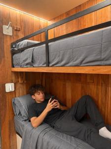 a man laying on a bed in a bunk bed at Destinar Tiny House in San Pedro