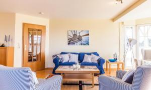 a living room with a blue couch and a table at Schleimündeblick in Olpenitz