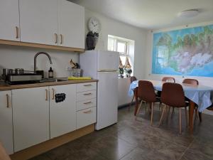 a kitchen with a table and a white refrigerator at Hrutafell Guesthouse in Hvolsvöllur