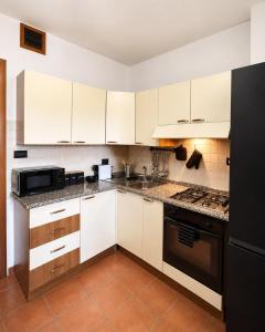 a kitchen with white cabinets and a black refrigerator at Appartamento Martina in Lanusei