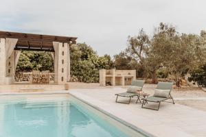 two chairs and a table next to a swimming pool at Siede la Terra - Trullo con piscina in Ceglie Messapica