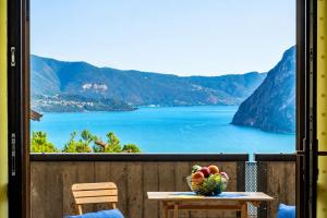 a table with a bowl of fruit on a balcony at Happy Guest Apartments - Lake Panorama & Pool in Riva di Solto