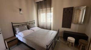 a bedroom with a bed with white sheets and a window at Ria's Garden House in Kassiopi