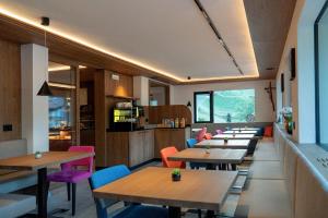 a restaurant with wooden tables and colorful chairs at Hotel Garni Morene in Selva di Val Gardena