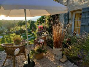 a patio with an umbrella and chairs and plants at Maison La Thébaïde in Castéra-Lectourois