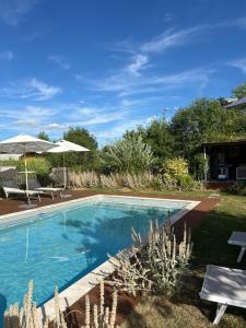 a swimming pool in a yard with chairs and an umbrella at Rêves & Rivière in Rivière