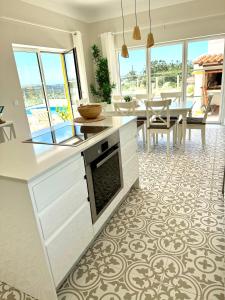 a kitchen with white cabinets and a dining room at Villa Ericeira in Ericeira