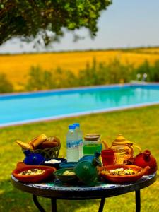 a table with plates of food and water bottles on it at Ferme Oasis de Fes in Fez