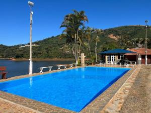 a large blue swimming pool next to a body of water at Chalés Talismã in Caconde