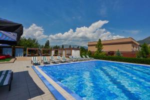 a swimming pool with lounge chairs next to a building at Charos Family Resort in Yusufkhona