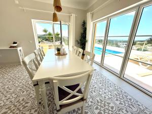 a white dining room with a white table and chairs at Villa Ericeira in Ericeira