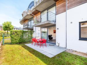 a patio with red chairs and a table in front of a house at Beth gelijkvloers in Sint-Idesbald