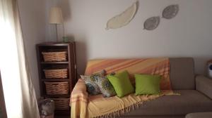 a living room with a couch with green pillows at Cantinho do Frangoneiro in Fortios +1 photo